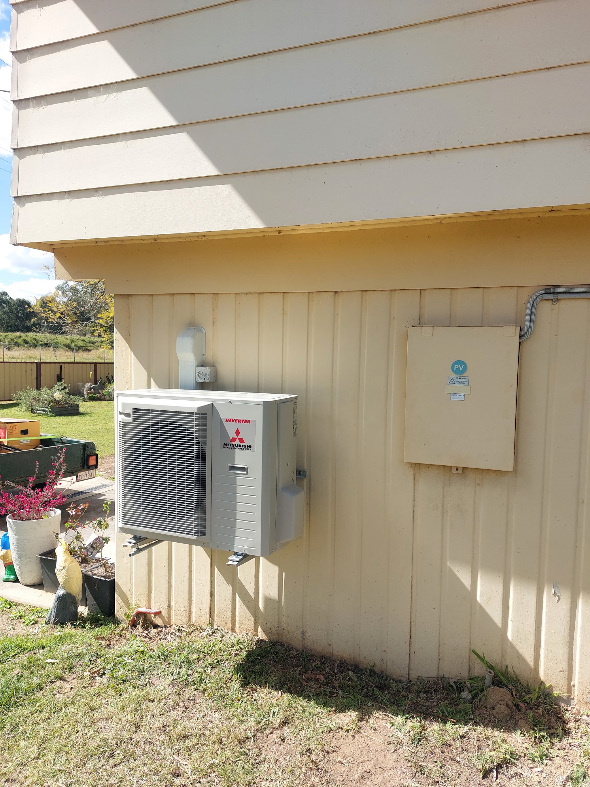 Air conditioning unit fitted beside a solar inverter on a rural shed
